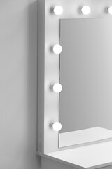 Modern makeup dressing table with mirror and lighting close-up.