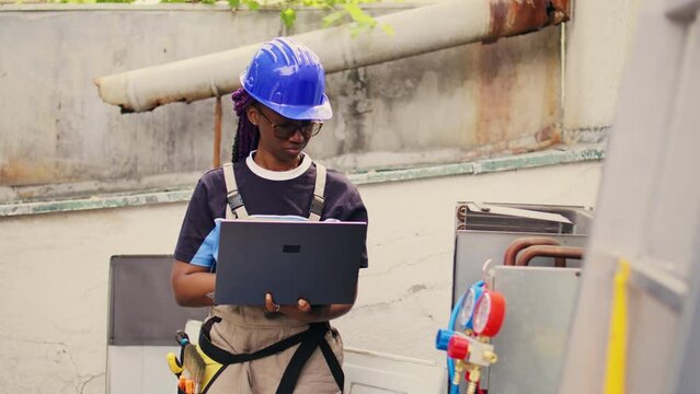 Experienced engineer working on external hvac system, holding laptop. Meticulous wireman optimizing outdoor condenser performance, ensuring it operates at maximum capacity