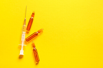 Ampules with syringe on yellow background