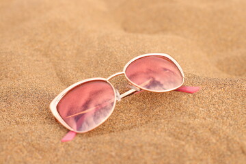 Fototapeta na wymiar Sunglasses gold on beach sand, summer vacation accessory