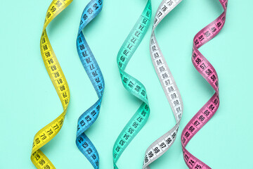 Colorful measuring tapes on turquoise background