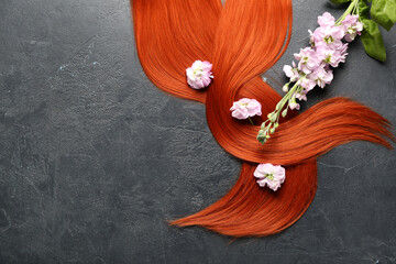 Ginger hair with beautiful flowers on dark background, closeup