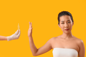 Beautiful Asian woman rejecting ampule on yellow background. Skin care concept