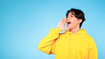 Korean Teenager Guy Shouting Loudly Looking Aside Over Blue Background