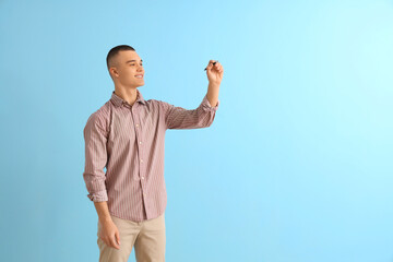 Fototapeta premium Male student with pen on blue background