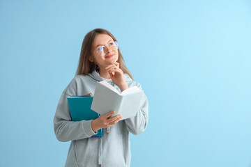 Obraz premium Happy female student with different books on blue background
