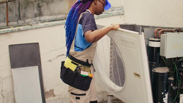 Proficient worker starting comission on defective air conditioner, meticulously disassembling condenser metal front coil panel. Capable electrician dismantling hvac system to check for dust