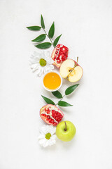 Composition with bowl of honey, ripe fruits, flowers and plant leaves on light background. Rosh hashanah (Jewish New Year) celebration