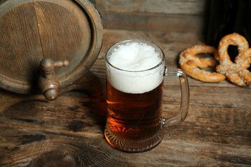 Mug of cold beer and barrel on wooden background. Oktoberfest celebration