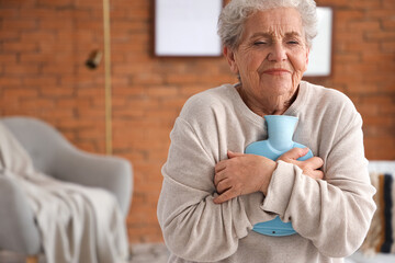 Ill senior woman with hot water bottle at home