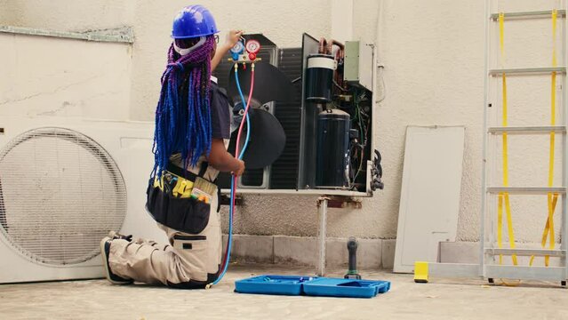 Capable electrician preparing for yearly condenser maintenance. Meticulous wireman unpacking toolset box with professional gear needed to repair faulty air conditioner internal components