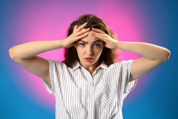 Young woman having panic attack on color background