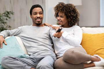 Happy relaxed black couple watching TV at home