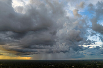 Obraz premium Dark stormy clouds forming on gloomy sky during heavy rainfall season over suburban town area in evening