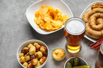 Glass of cold beer and different snacks on grey background. Oktoberfest celebration