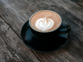 A coffee late art with vintage tone in a black mug on an old wooden table