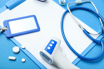 Composition with clipboard, pills and medical equipment on blue background