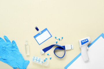 Badge, tourniquet, pills, infrared thermometer, medical gloves and clipboard on beige background