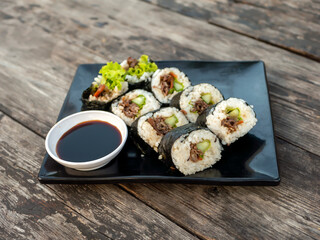 Homemade beef shusi on a black plate & old wooden table