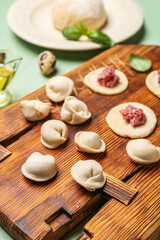 Fototapeta na wymiar Wooden board with uncooked dumplings on table