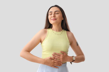 Young woman gesturing on light background