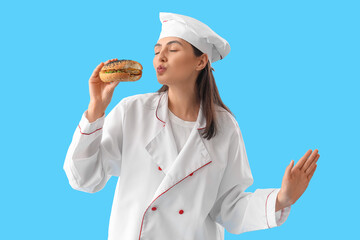 Female chef with tasty burger blowing kiss on blue background
