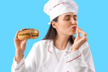 Female chef with tasty burger on blue background, closeup