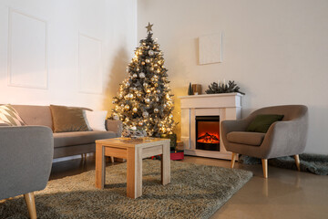 Interior of living room with Christmas tree, grey sofa and armchairs