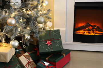 Gift boxes under Christmas tree near fireplace in living room