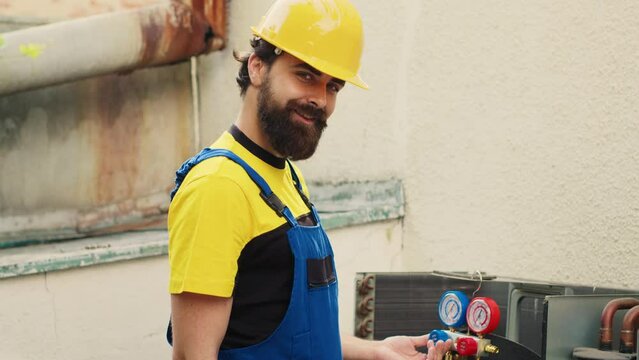 Revealing portrait shot of trained repairman doing annual condenser maintenance, preparing freon barometer before starting work. Expert repairman reading pressure of liquids and gases in condenser