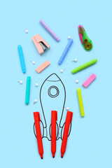 Creative composition with drawn rocket and different stationery on blue background