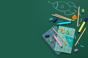 Creative composition with drawn rocket and different stationery on green chalkboard