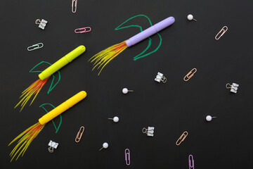 Creative composition with drawn rockets and different stationery on black chalkboard