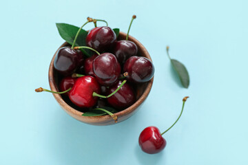 Fototapeta na wymiar Bowl with sweet cherries on blue background