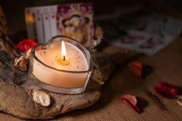 Attributes for love magic and fortune telling on cards, a candle on a wooden background, dry rose...