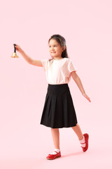 Little schoolgirl with bell on pink background