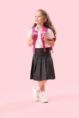 Little schoolgirl with backpack on pink background