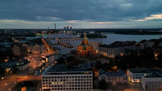 Lights from buildings and historic church in Helsinki harbor at dawn