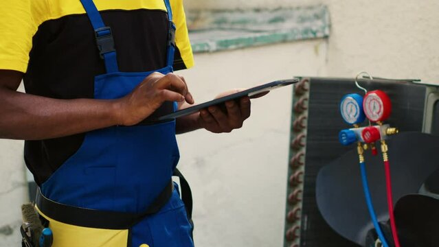 Revealing portrait shot of happy trained engineer with tablet checking refrigerant levels in condenser while using manometers to accurately measure the pressure in HVAC system