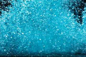 Naklejka na ściany i meble Explosion metallic blue glitter sparkle. sky Glitter powder spark blink celebrate, blur foil explode in air, fly throw blue glitters particle. Black background isolated, selective focus Blur bokeh