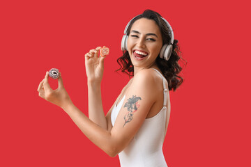 Young woman in headphones with jelly candies on red background