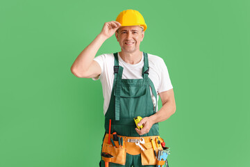 Mature builder with tape measure on green background