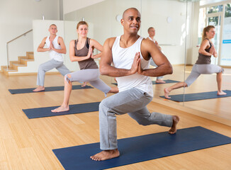 Obraz premium Positive man practicing yoga lesson at group class, maintaining healthy lifestyle