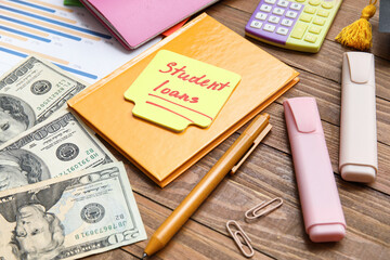 Sticky note with text STUDENT LOANS, notebook, markers and dollar banknotes on wooden table