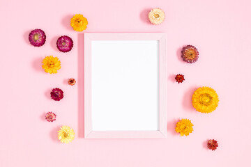 Floral background with beautiful flowers. Flat lay, top view of photo frame and flowers on pastel pink background.
