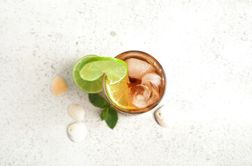 Glass of cold Cuba Libre cocktail and seashells on white background