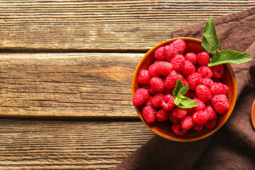 Bowl with fresh raspberries and mint on wooden background