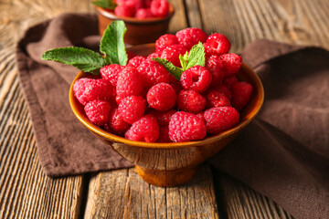 Bowl with fresh raspberries and mint on wooden background