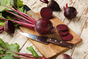 Board of fresh beets with green leaves on wooden background