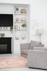 Stylish room interior with beautiful fireplace, TV set, armchairs and shelves with decor